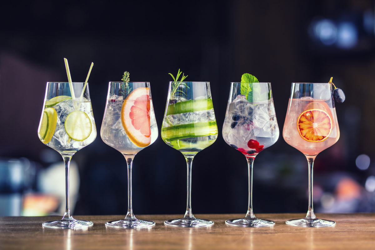 alkohol drinky Five colorful gin tonic cocktails in wine glasses on bar counter Na zdravie, Cheers, Prost! Alkohol oficiálne zlepšuje naše jazykové schopnosti