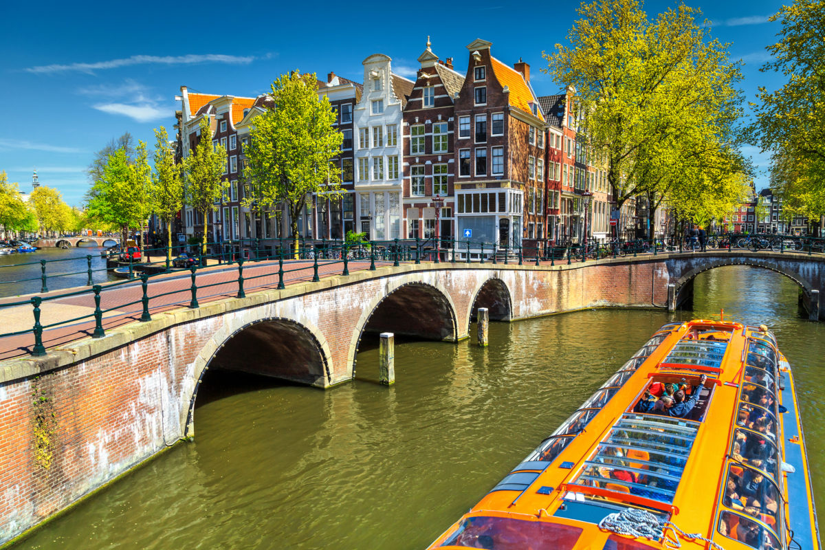 Typical Amsterdam canals with bridges and colorful boat, Netherlands, Europe Amsterdam chce rovnováhu medzi miestnymi a turistami