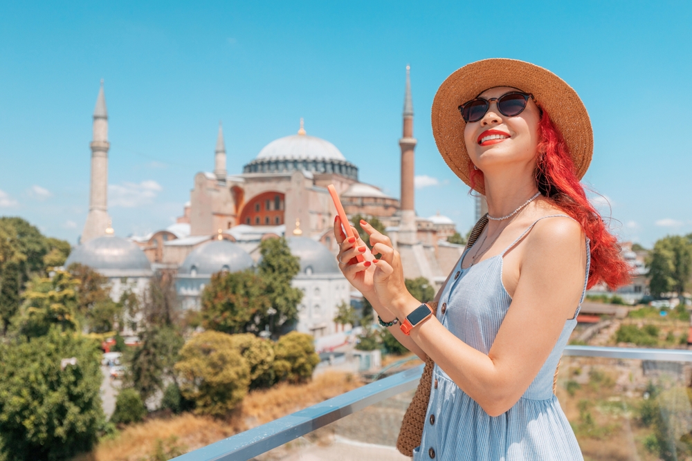 A,Stylish,Woman,Tourists,In,Istanbul,,Browsing,Her,Smartphone,And turistka s telefonom v ruke pred mesitou v istanbule