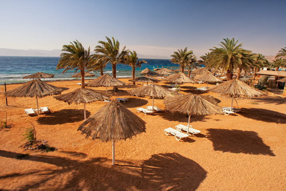 Aqaba,Beach,With,Sunshades,And,Deckchairs. LACNÁ EXOTIKA: Jordánska destinácia Ammán spiatočne z Viedne od 59€!