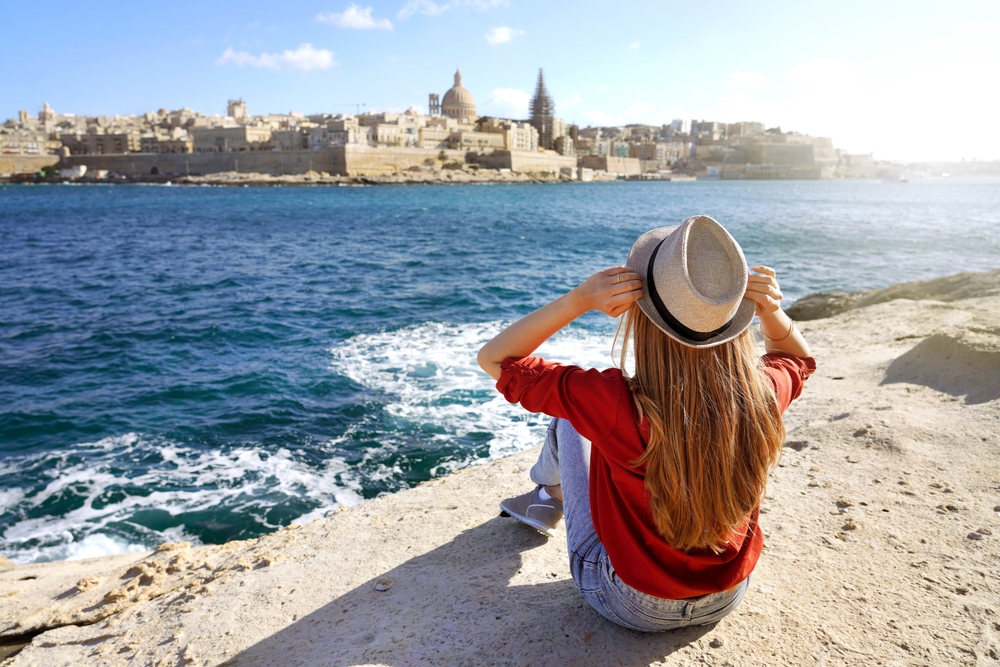 Young,Traveler,Woman,Holds,Hat,Looking,At,Valletta,Old,Town malta