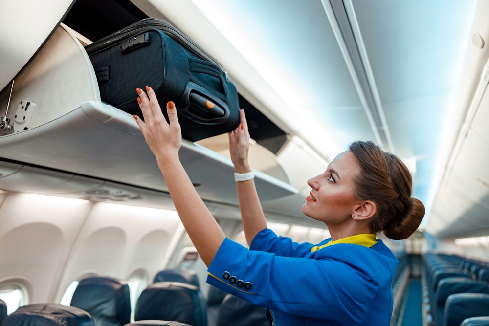 Woman,Flight,Attendant,Or,Air,Hostess,Placing,Travel,Bag,In Príručná batožina zadarmo? EÚ chce pretlačiť zásadnú zmenu pre aerolinky